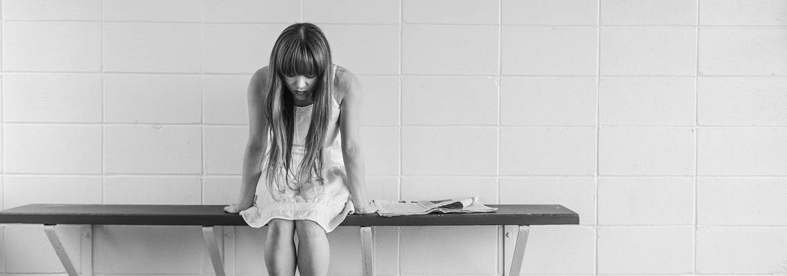 Ein deprimiertes Mädchen sitzt auf einer Bank