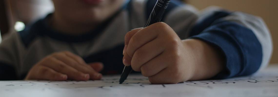 Ein Kind schreibt etwas auf ein Blatt Papier
