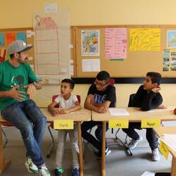 Die Schülerinnen und Schüler der Sprachlernklasse erarbeiten in der Albert-Einstein-Schule mit dem Rapper Spax den Songtext.