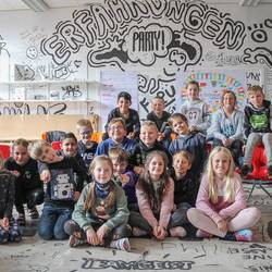 Schülerinnen und Schüler der Grundschule Ingeln-Oesselse präsentieren in einem schwarzweiß bemalten Raum die Ergebnisse des Projektes miteinanderfüreinander..