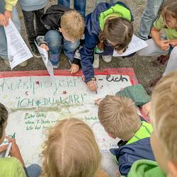 Die Schülerinnen und Schüler aus dem Projekt "Ich + Du = Wir!" stellen ihre Ergebnisse bei der Vernissage am 19. Juni 2024 vor dem Mitmachgarten im Park der Sinne in Laatzen vor.